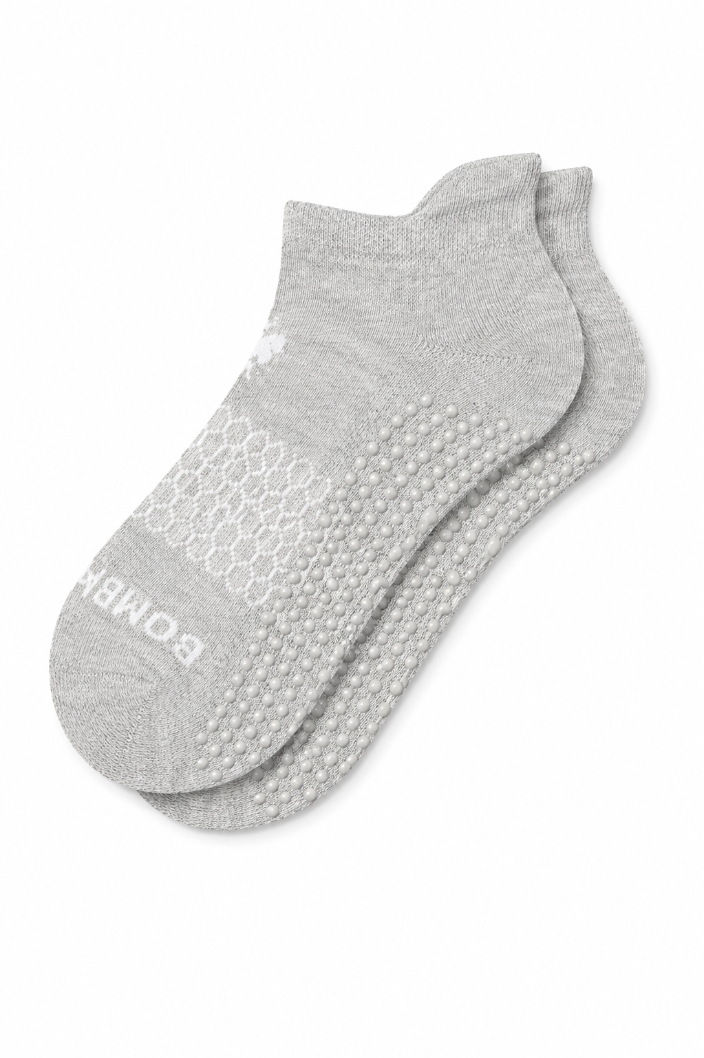 A pair of light gray low-cut athletic socks with textured grip dots on the sole and a white BOMBAS logo printed on the toe, displayed on a clean white background and included in our Comfort and Care Packages for women.